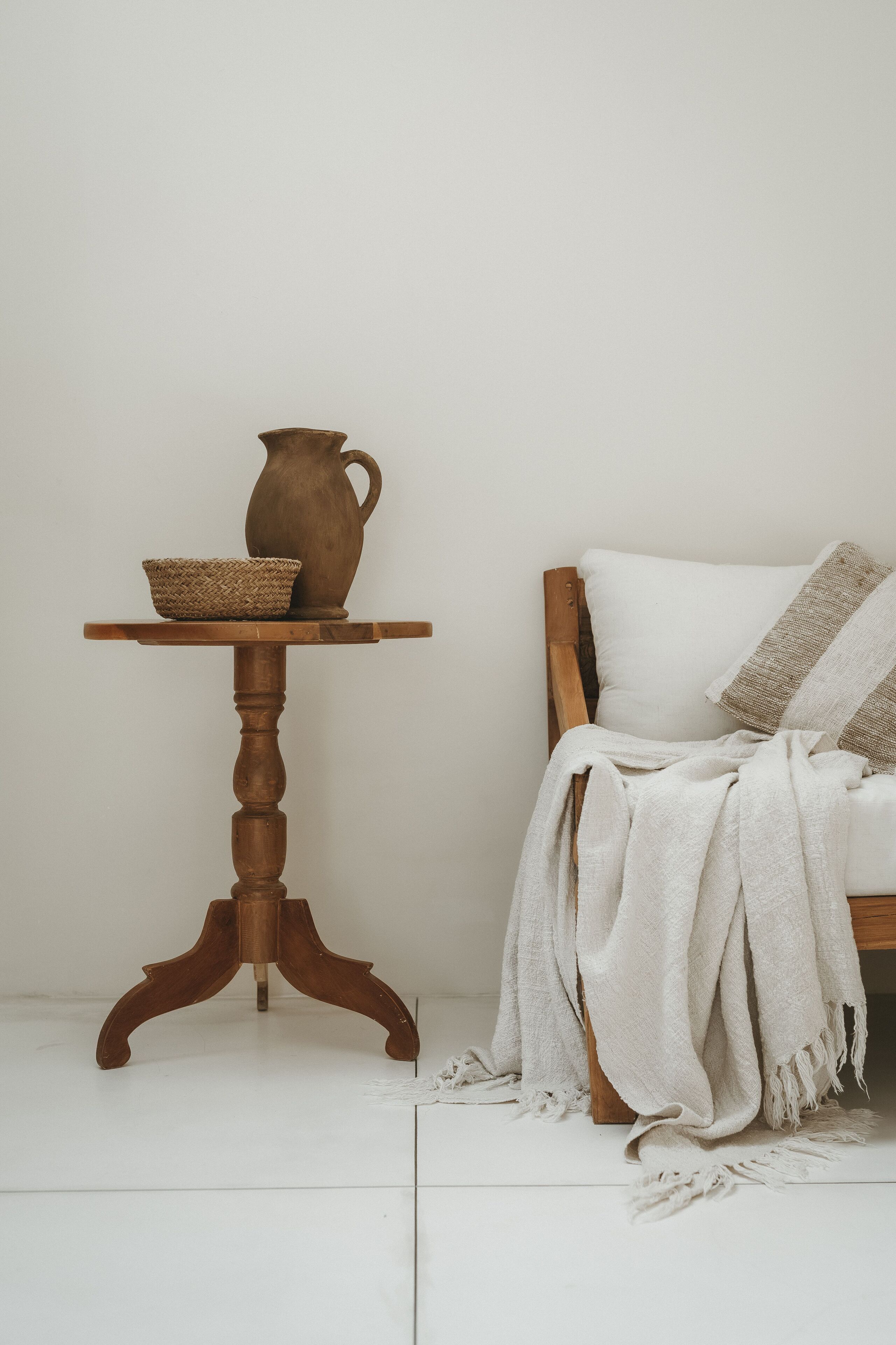 Une table en bois sur laquelle sont posés un panier tressé et un pichet en céramique.