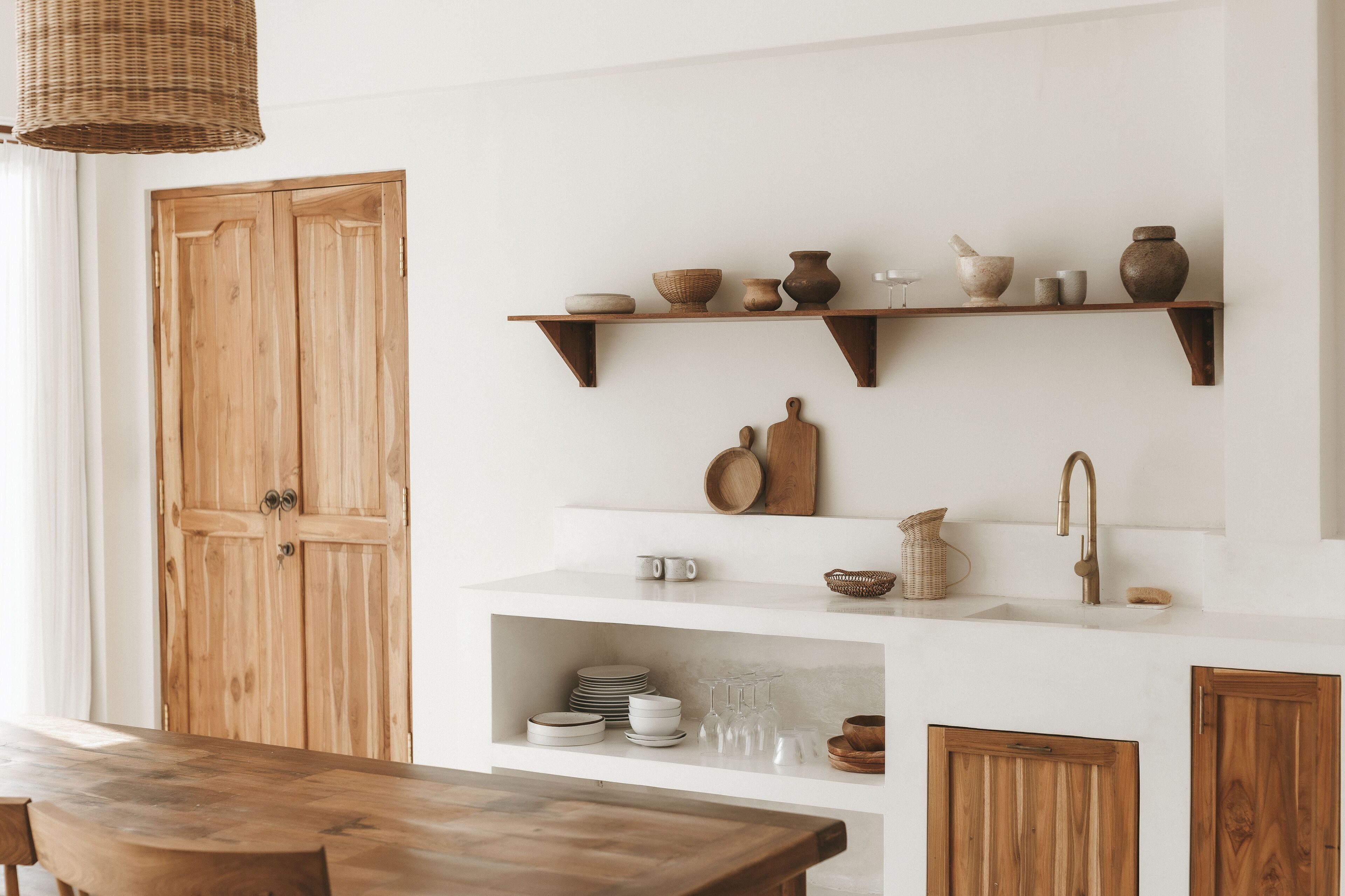 Eine Küche mit Holzschränken, einem Holztisch und Regalen voller Küchenutensilien.
