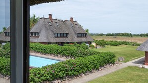 Ein Haus mit Strohdach, einem Swimmingpool und üppiger Bepflanzung.