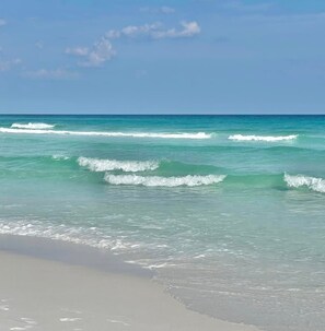 A beach with clear turquoise water and gentle waves.