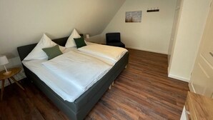 Makuuhuoneessa on suuri sänky, yöpöytä, lamppu, tuoli ja seinällä taulu.