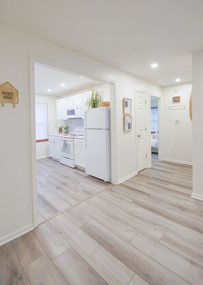 A modern kitchen with white cabinetry, a refrigerator, and a microwave. - [4] StayAwhile: The Modern Retreat, Steps from Mass St! (Lawrence)
