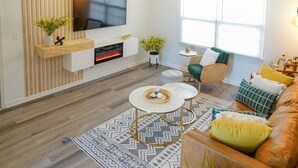 Un salon moderne doté d’un téléviseur à écran plat, d’une cheminée, d’un canapé et d’une table basse.