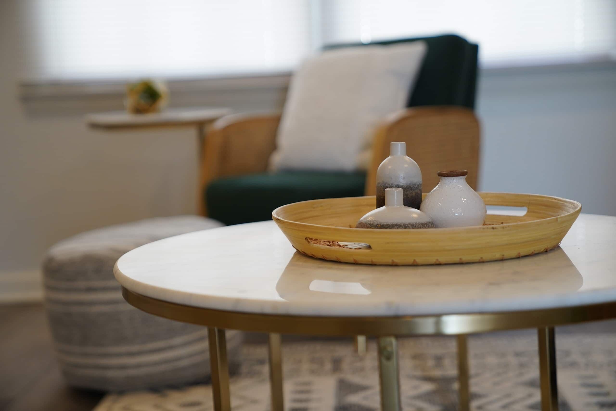 A round table with a white surface and a wooden tray holding two white bottles and a small container.