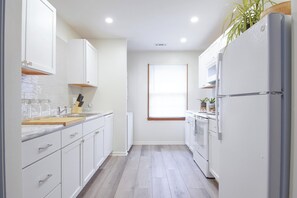 Una cocina moderna con armarios blancos, encimera de madera y horno empotrado.