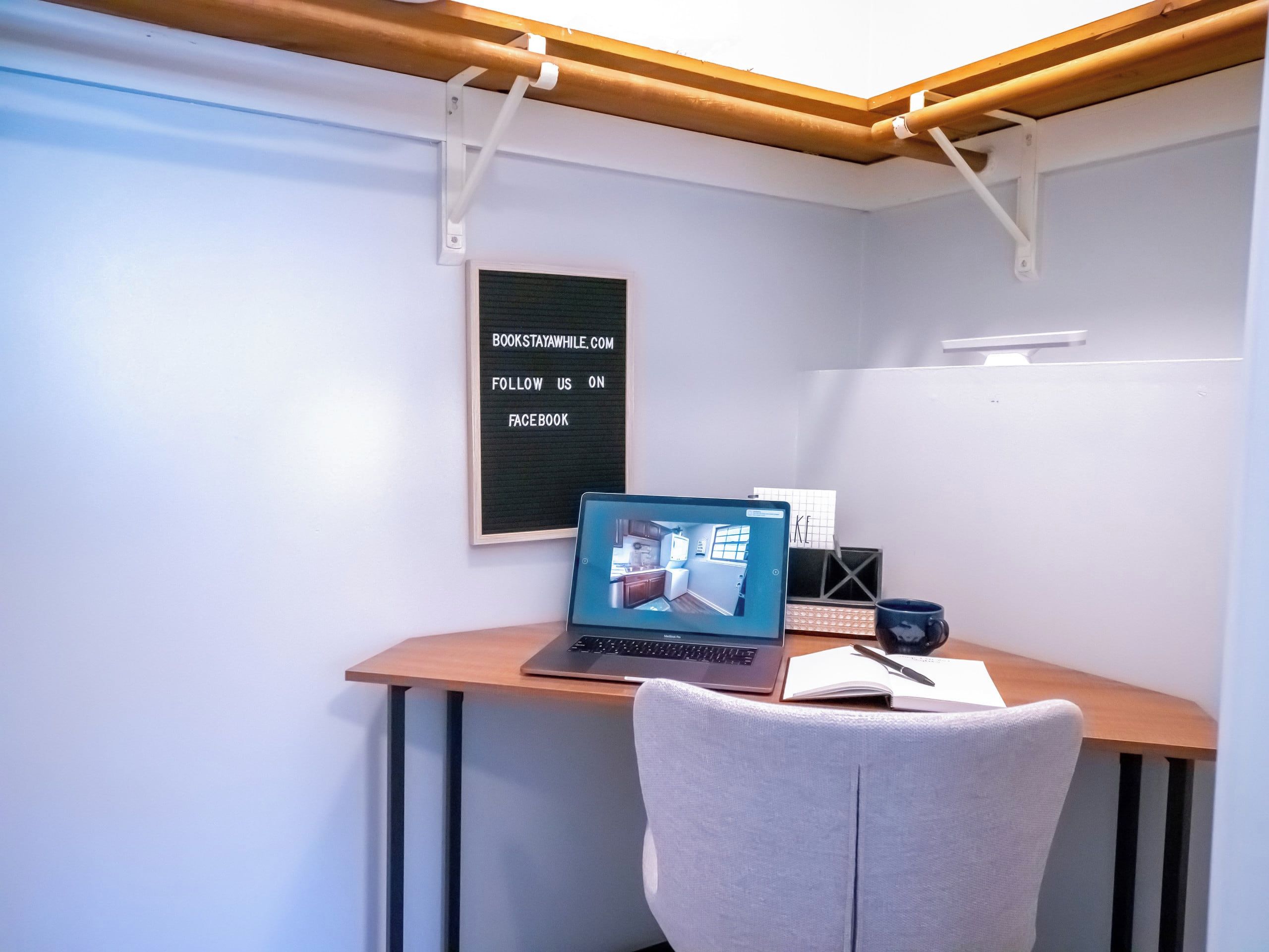 A workspace with a laptop, a framed sign, and a chair.