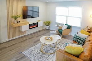 A modern living room with a flat-screen TV, a fireplace, a sofa, and a coffee table.