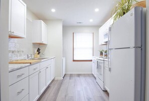 A modern kitchen with white cabinets, a wooden countertop, and a built-in oven. - [4] StayAwhile: The Modern Retreat, Steps from Mass St! (Lawrence)