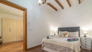 Een slaapkamer met een bed, nachtkastjes, een kledingkast en een houten plafond.