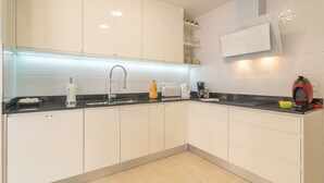 Een moderne keuken met witte kasten, een zwart aanrecht en een ingebouwde magnetron.