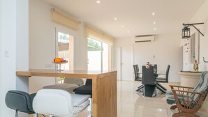 Een moderne keuken met een houten aanrecht, barstoelen en een eethoek met tafel en stoelen.