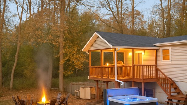 A cabin with a hot tub, deck, and fire pit.