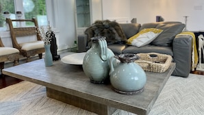 A living room with a wooden coffee table, two ceramic pitchers, and a woven basket.