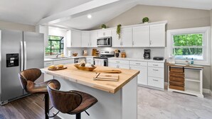 Une cuisine moderne avec des armoires blanches, un îlot central en bois et un réfrigérateur en acier inoxydable.