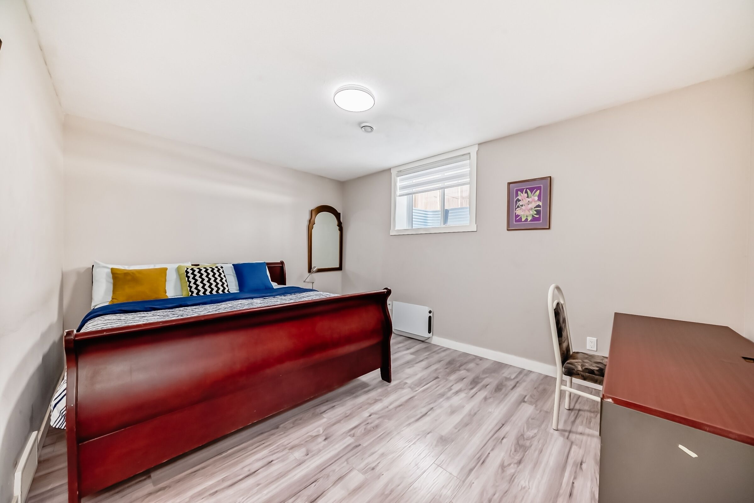 A bedroom with a wooden bed, a desk, and a chair.
