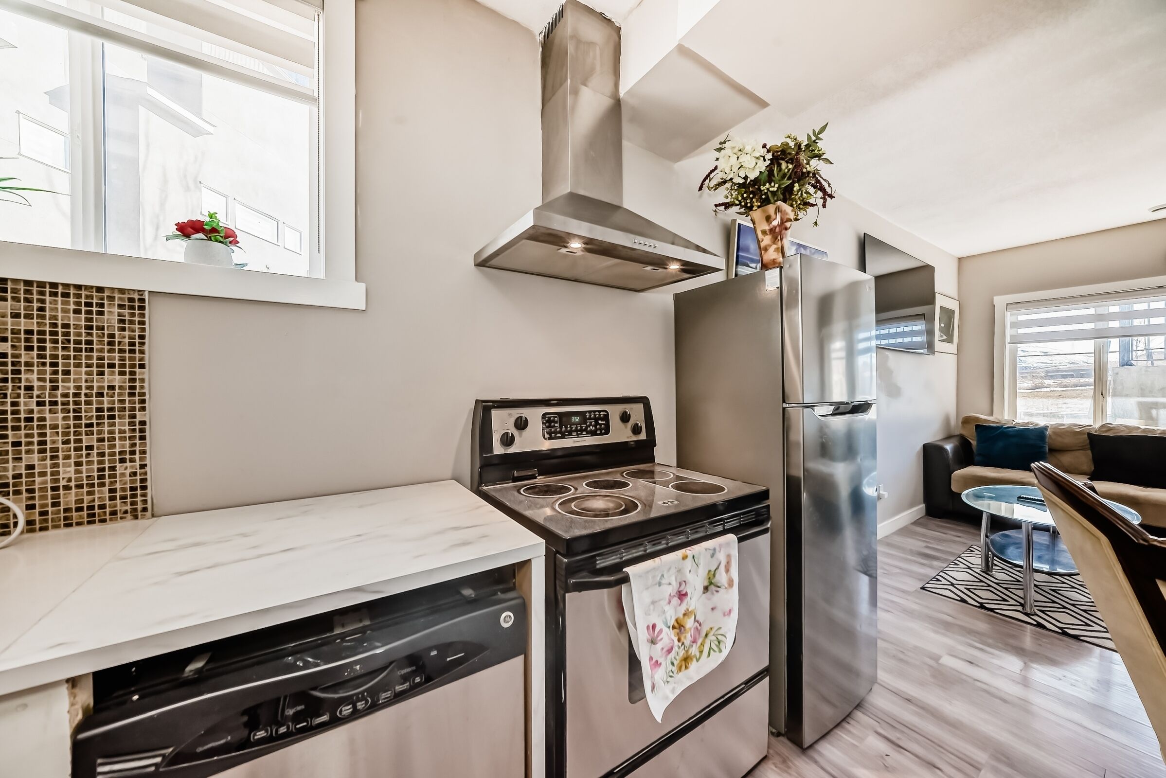 A modern kitchen with a stainless steel stove, dishwasher, and refrigerator.
