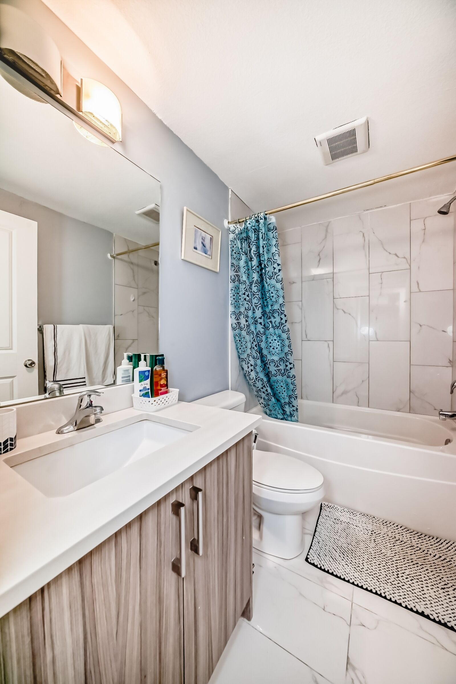 Un baño moderno con lavamanos, tocador y bañera blancos.