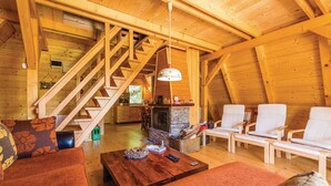 L’intérieur d’un chalet en bois chaleureux et accueillant, avec une cheminée, un escalier en bois et un coin salon comprenant deux canapés et une table basse.
