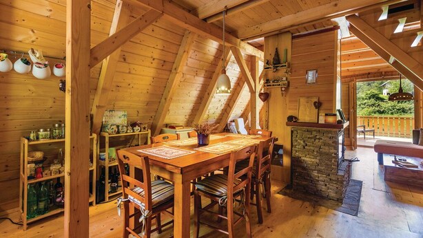 Un intérieur en bois comprenant une table à manger, des chaises, une cheminée en pierre et une structure de plafond en bois.