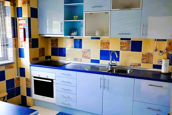 A kitchen with a blue countertop, white cabinets, and a stainless steel sink.