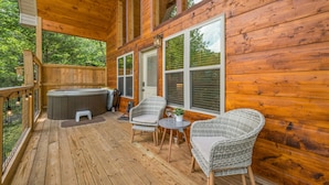 A wooden deck with a hot tub, wicker chairs, and a small table with a plant. - Perfect Family Cabin for 4–5 • Kids' Loft, Arcade, Hot Tub, Easy Drive (Gatlinburg)