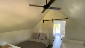 Un dormitorio con techo inclinado, una cama con cabecera, una mesita de noche y un ventilador de techo.