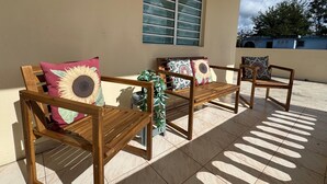 A patio with wooden furniture, including two chairs and a bench, each with a sunflower cushion. - Modern 3BR Home in Fontana Village with Power & Water Backup (Carolina)