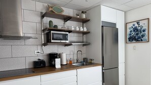 A modern kitchen with a stainless steel refrigerator, wooden shelves, and a microwave. - Modern 3BR Home in Fontana Village with Power & Water Backup (Carolina)