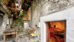 A rustic stone staircase leading to a dining area with a checkered floor and a wooden table with chairs. - Rustico Caterina - Corippo, Corippo, Val Verzasca, Switzerland (Corippo, Val Verzasca)