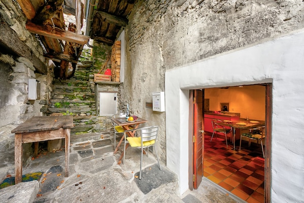 A rustic stone staircase leading to a dining area with a checkered floor and a wooden table with chairs. - Rustico Caterina - Corippo, Corippo, Val Verzasca, Switzerland (Corippo, Val Verzasca)