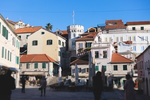 Una calle estrecha con edificios históricos, una torre destacada y un cielo azul despejado.