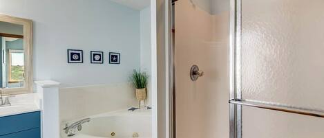 Une salle de bain avec une baignoire blanche, un meuble-lavabo en bois et un miroir. Trois tableaux encadrés sont accrochés au mur.