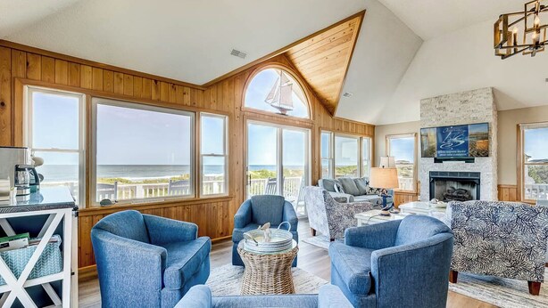A spacious living room with large windows, a fireplace, and a view of the ocean. - What the Shell | Oceanfront | Private Pool, Hot Tub, Community Pool (Corolla)