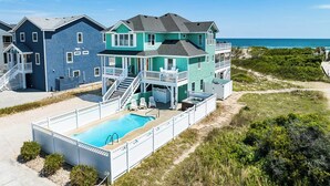 A two-story house with a pool, a covered patio, and a view of the ocean. - What the Shell | Oceanfront | Private Pool, Hot Tub, Community Pool (Corolla)