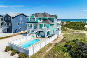 A two-story house with a pool, a covered patio, and a view of the ocean. - What the Shell | Oceanfront | Private Pool, Hot Tub, Community Pool (Corolla)