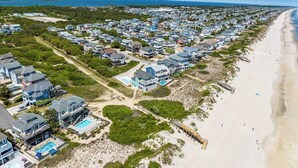 An aerial view of a coastal residential area with houses, a beach, and a pier. - What the Shell | Oceanfront | Private Pool, Hot Tub, Community Pool (Corolla)