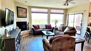 A spacious living room with a fireplace, a television, and a ceiling fan. - Beautiful Mountain Views and a spacious relaxing home in NW Tucson. (Tucson)