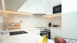Una cocina moderna con armarios blancos, un lavaplatos de acero inoxidable y un horno empotrado.