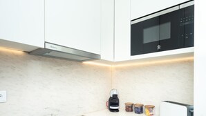 Una cocina moderna con armarios blancos, una placa de inducción Bosch, un tostador Bosch y una cafetera Bosch.