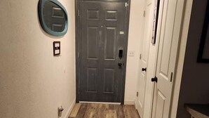 A hallway with a wooden floor, a dark door, and white walls. - Newly remodeled 3b (Panama City Beach)