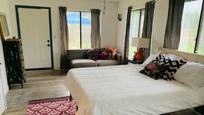 A bedroom with a large bed, a sofa, a dresser, and a window with curtains. - Newly remodeled 3b (Panama City Beach)