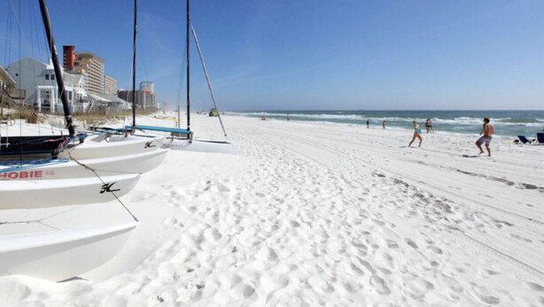 A beach with white sand, a few people, and sailboats. - Newly remodeled 3b (Panama City Beach)