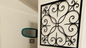 A bar area with two stools, a small table with a bottle and glasses, and a decorative metal wall piece. - Newly remodeled 3b (Panama City Beach)