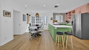A modern kitchen with a central island, green cabinets, and a stainless steel refrigerator. - Chic Modern Designed Home w/ Private Studio (Newport Beach)