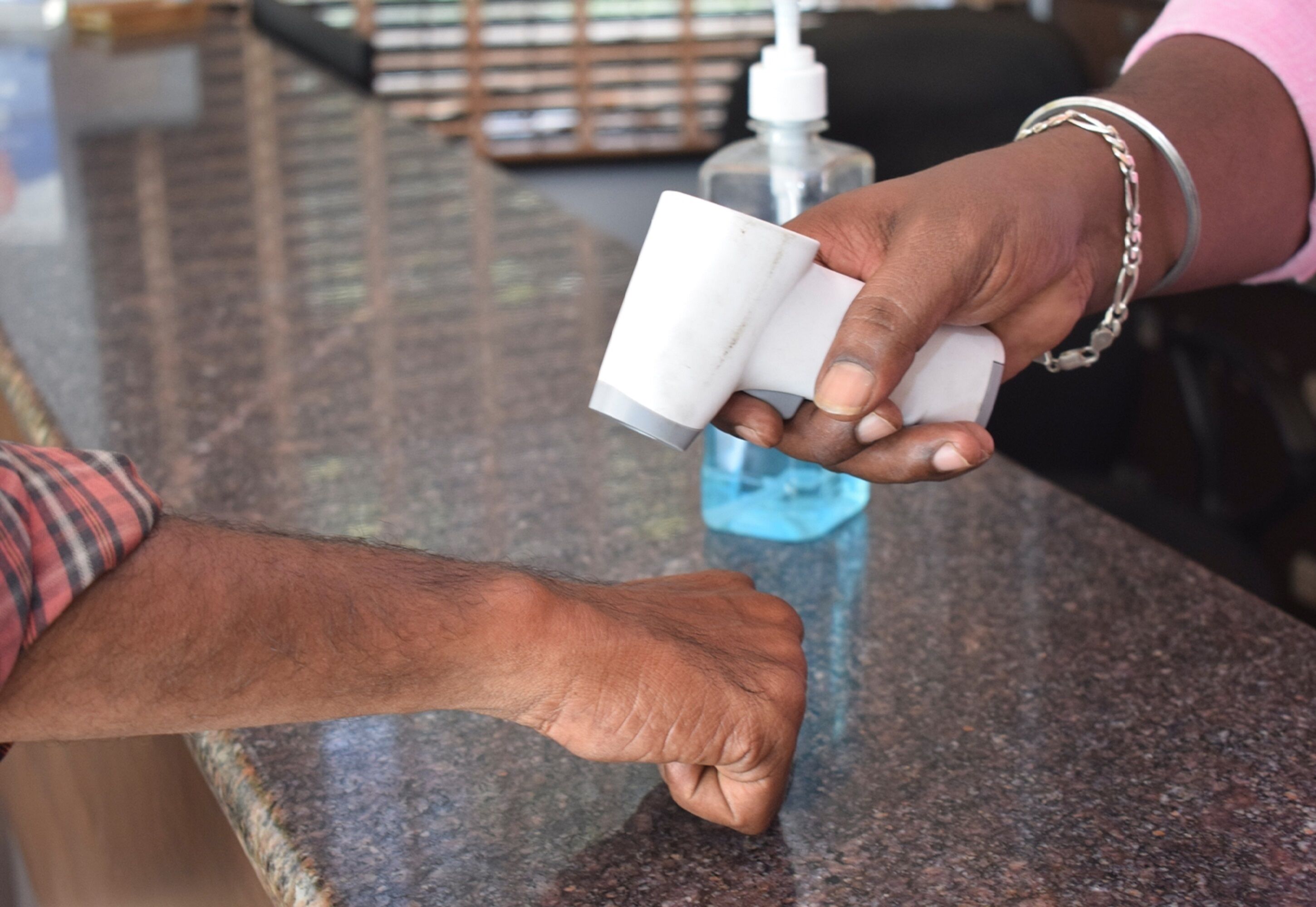 A person holding a white object, possibly a bottle, near a granite countertop.
