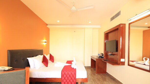 Une chambre d’hôtel avec un lit, un bureau, une télévision et un miroir.