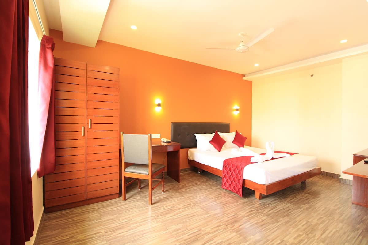 Ein Hotelzimmer mit Bett, Schreibtisch, Stuhl, Kleiderschrank und Deckenventilator.
