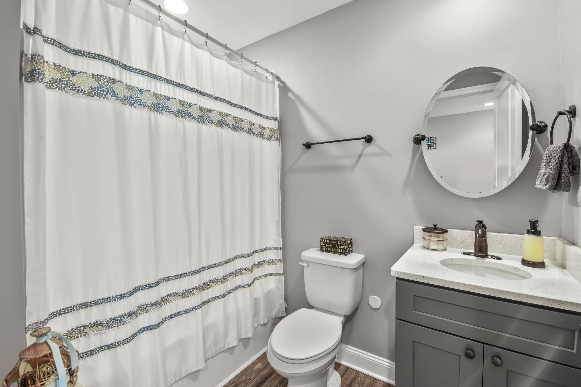 Ein Badezimmer mit Toilette, Waschbecken und Spiegel sowie einer Duschkabine mit dekorativem Muster.