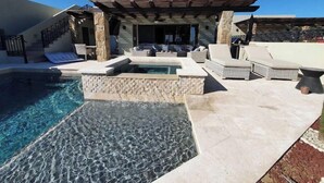 Un espace piscine doté d’un jacuzzi, de chaises longues et d’une pergola.