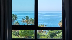 Ein großes Fenster mit Blick auf das Meer und Palmen.